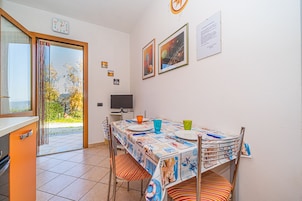 A dining area with a table set for two, a television, and a view of the outdoors.