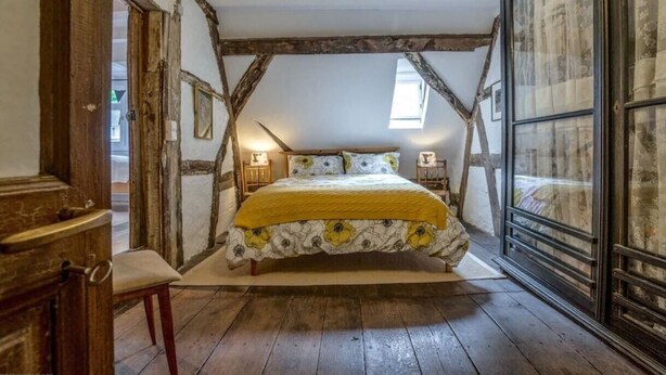 Ein Schlafzimmer mit Holzboden, einem Bett mit floralem Überwurf und einem großen Fenster mit Aussicht.