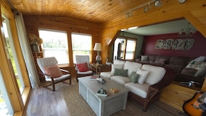 A cozy cabin interior with a wooden ceiling, a large sofa, a coffee table, and a guitar. - Have an unforgettable getaway at a family sized beach house with private beach! (Steuben)