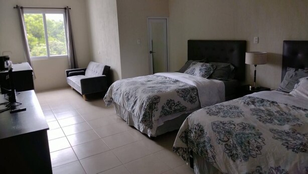 A bedroom with two beds, a desk, a chair, and a window with curtains. - Family Studio with all the comforts, centrally located. (Jalapa)