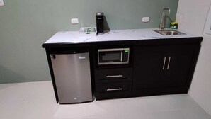 A compact kitchen with a built-in microwave, a small refrigerator, and a sink. - Family Studio with all the comforts, centrally located. (Jalapa)