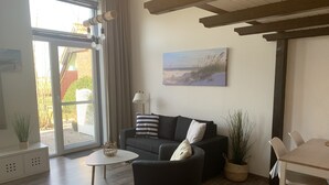En moderne stue med sofa, sofabord og spiseområde med stole.