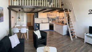 En moderne lejlighed i loftstil med spiseplads, køkken og soveværelse i loftet.