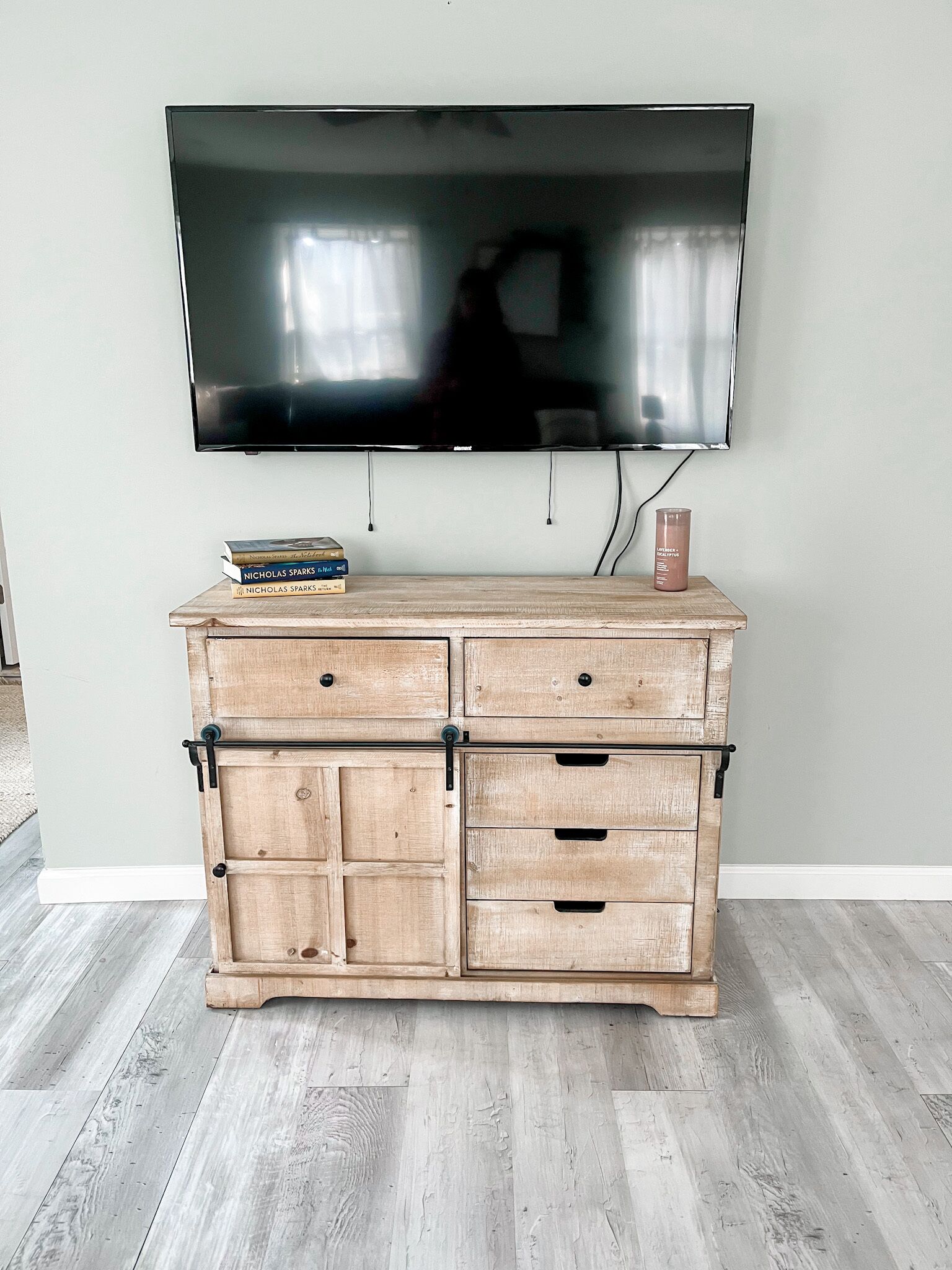 Un meuble en bois avec des tiroirs, et un téléviseur à écran plat fixé au mur juste au-dessus.