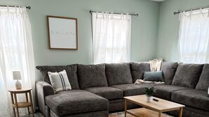 A living room with a sectional sofa, a coffee table, and a patterned rug.