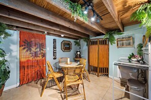Ein rustikales Interieur mit Holzbalkendecke, einem Glastisch mit Stühlen, einer Holzwand und einem Waschbecken.
