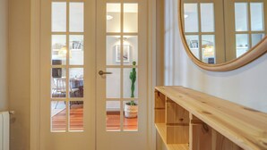 A room with a wooden floor, a white door with glass panels, a wooden bench, and a round mirror on the wall. - Balmins Surf by Hello Homes Sitges (Sitges)