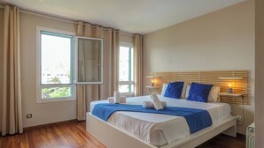A modern bedroom with a large bed, two bedside tables, and a window with curtains. - Balmins Surf by Hello Homes Sitges (Sitges)