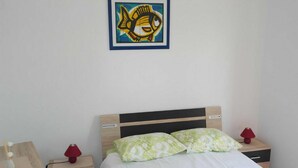 A neatly arranged hotel room with a bed, bedside tables, and a framed artwork on the wall. - Apartment Račić (Bol)