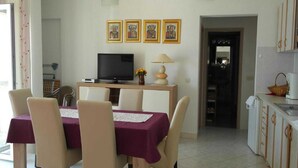 A dining area with a table set for four, a television, and a lamp on a wooden console. - Apartment Račić (Bol)