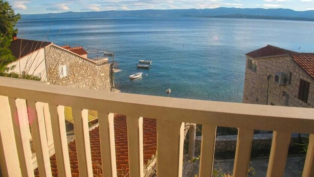 A coastal view with stone buildings, clear blue sea, and boats. - Apartment Račić (Bol)