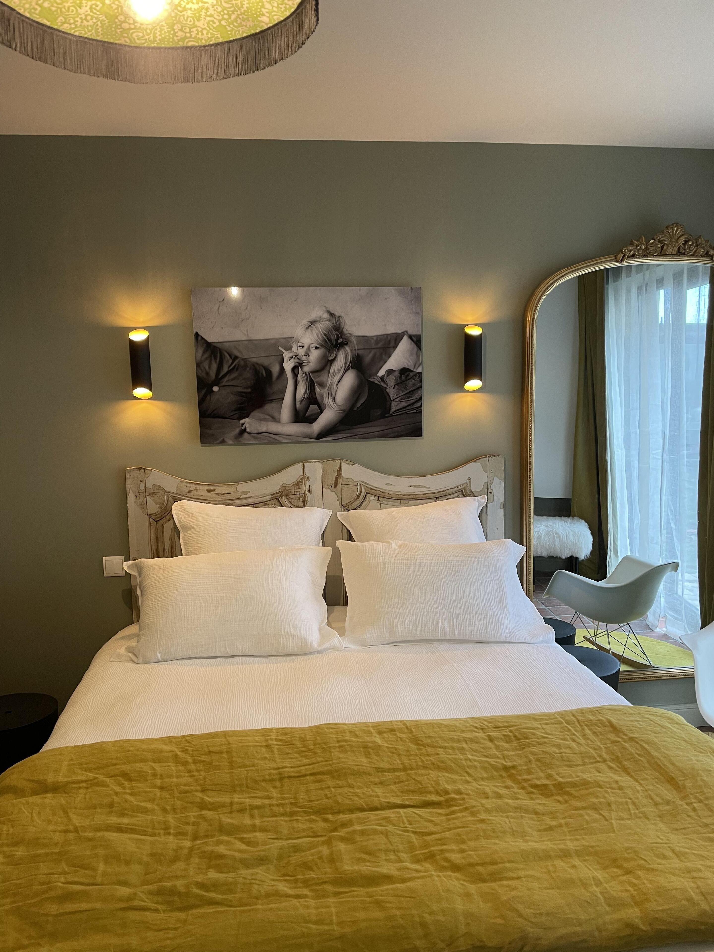 A bedroom with a bed, a large mirror, and a wall-mounted picture.