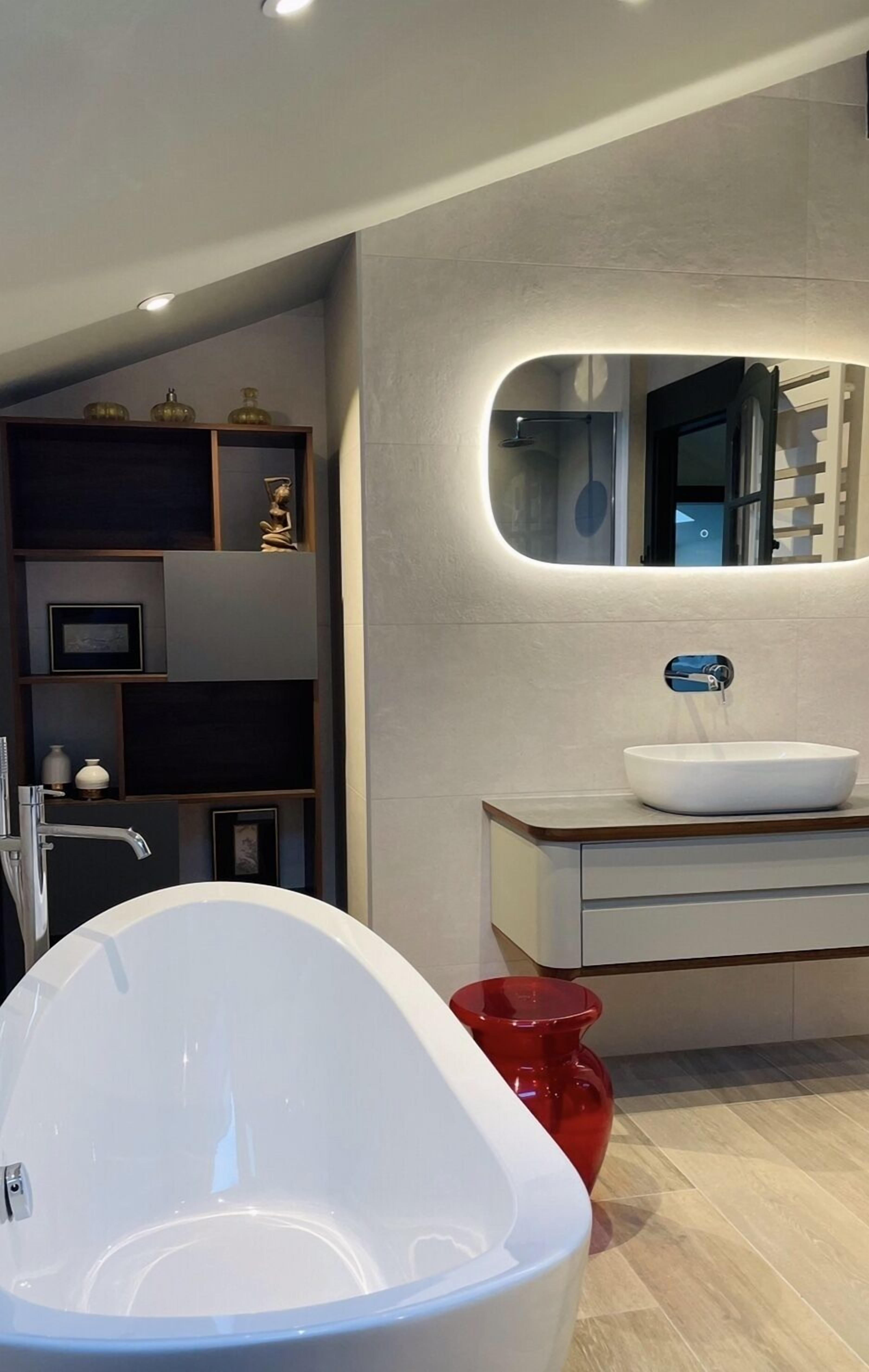 Un bany modern amb una banyera autònoma, un lavabo amb un rentapins i un mirall sobre el lavabo.