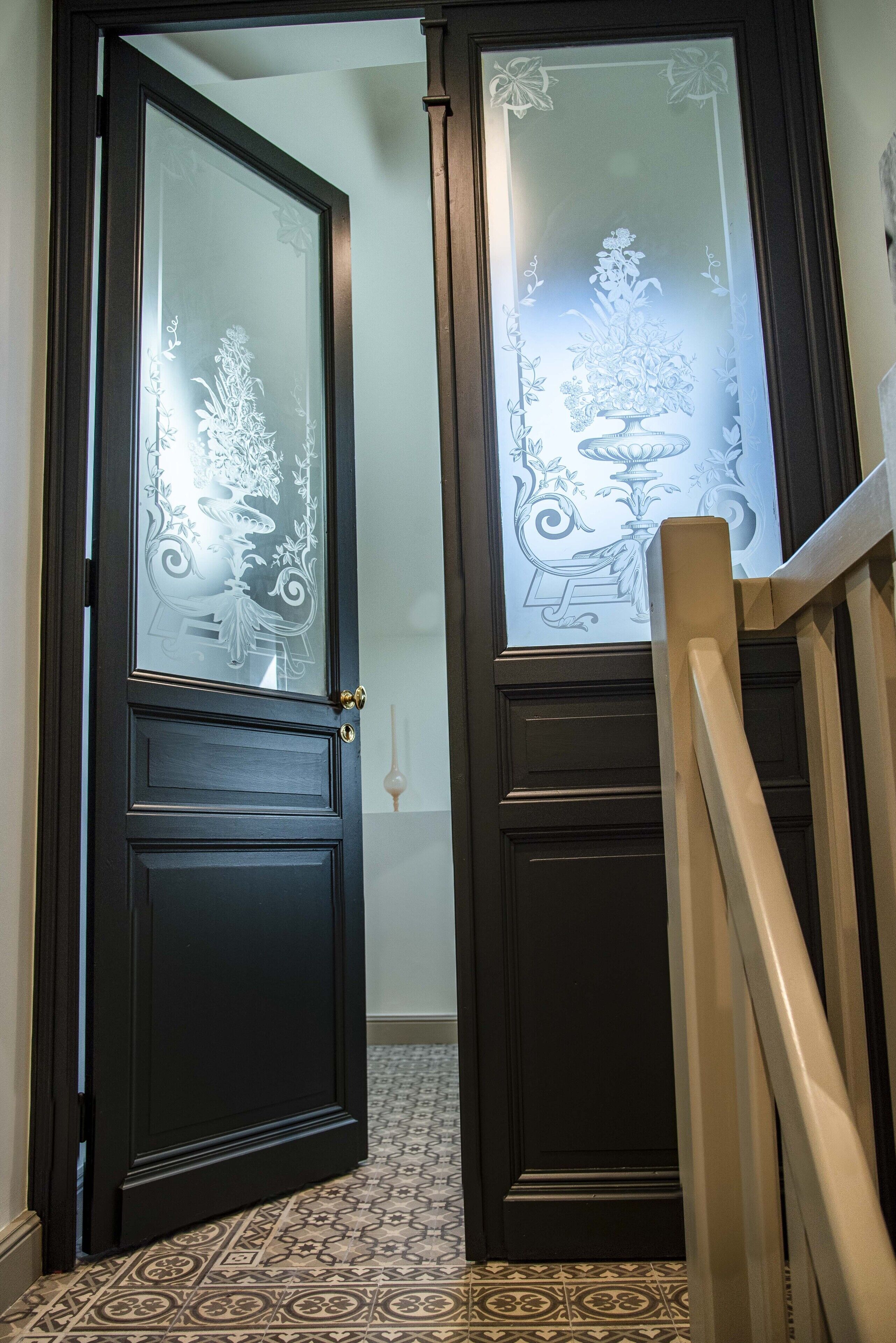 A dark wooden door with frosted glass panels and decorative floral patterns.