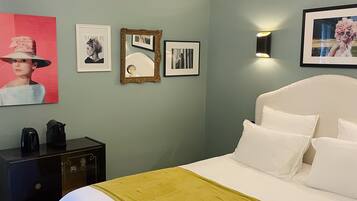 Un dormitorio ordenado con cama, mesitas de noche, una lámpara de pared y cuadros enmarcados.