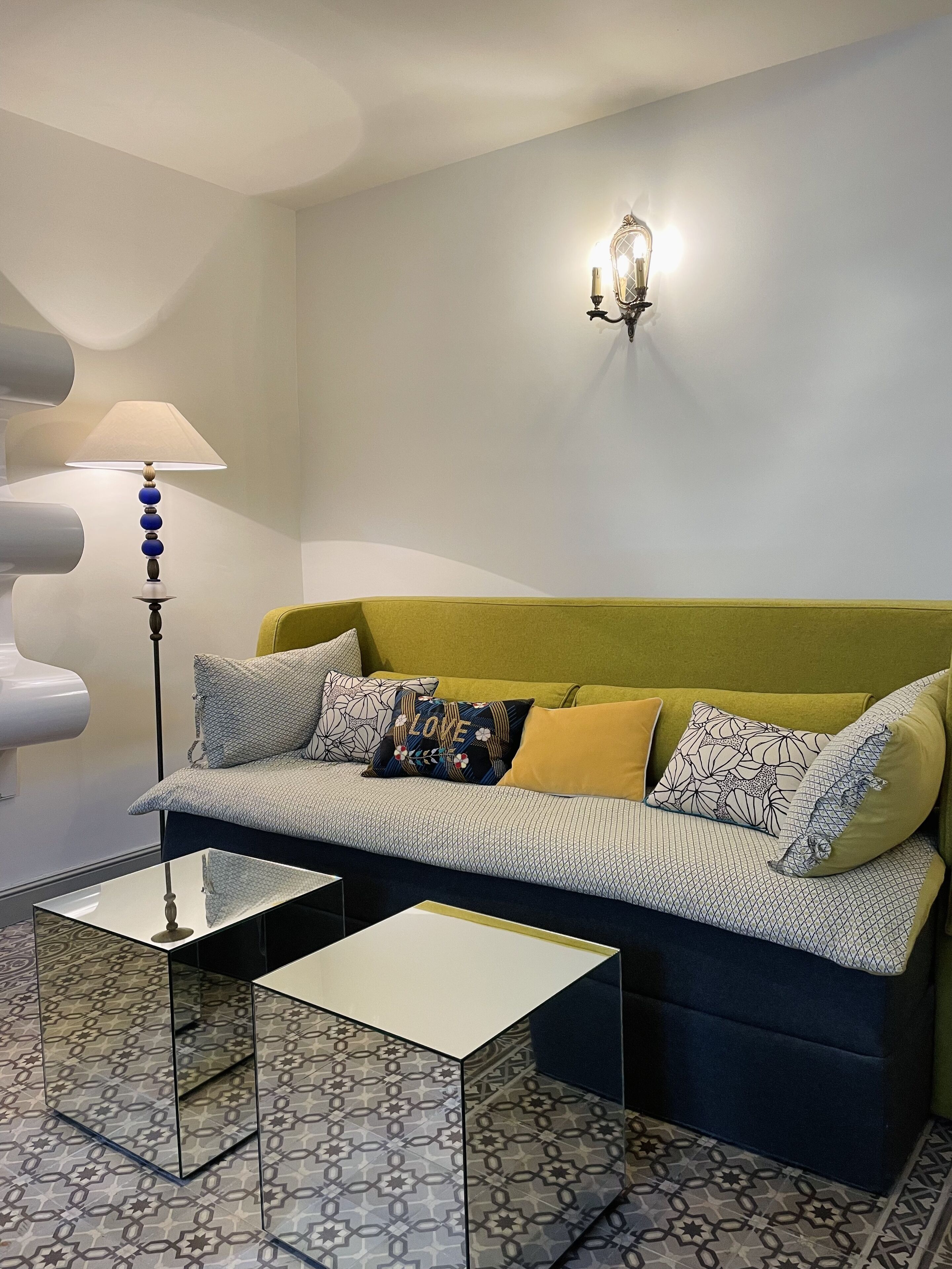 Uma sala de estar moderna com um sofá, um abajur e ladrilhos estampados.