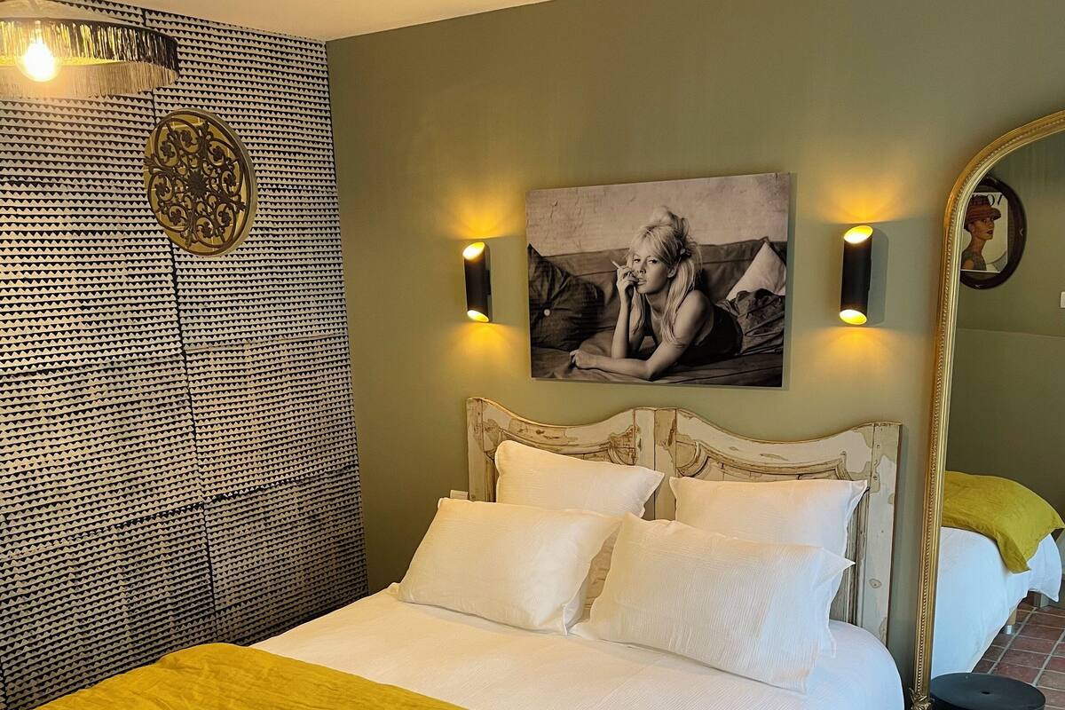 Ein Bett mit einer gelben Decke, einem gemusterten Kopfteil und einem an der Wand hängenden Bild.