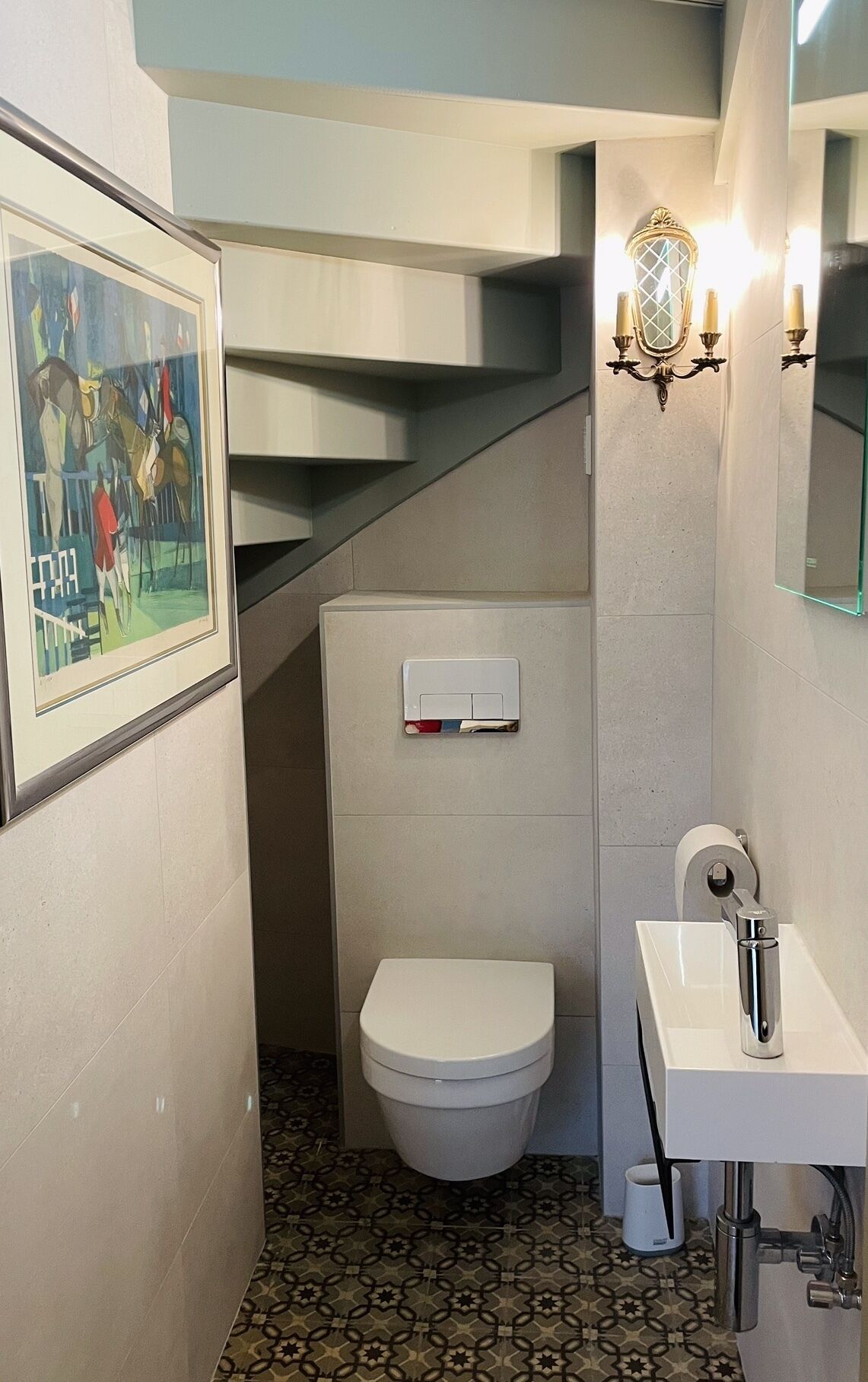 Un baño pequeño con inodoro, lavamanos y un cuadro enmarcado en la pared.