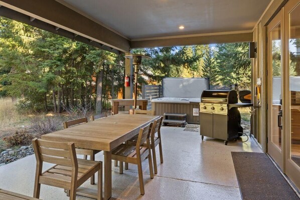 Un patio al aire libre con una mesa y sillas de madera, una parrilla y un extintor.