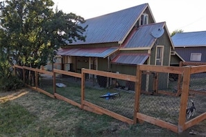 A house with a metal roof, a wooden fence, and a satellite dish.