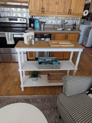 Una cucina con mobili in legno, un piano cottura in acciaio inossidabile, una macchina da caffè e un espositore per piatti.
