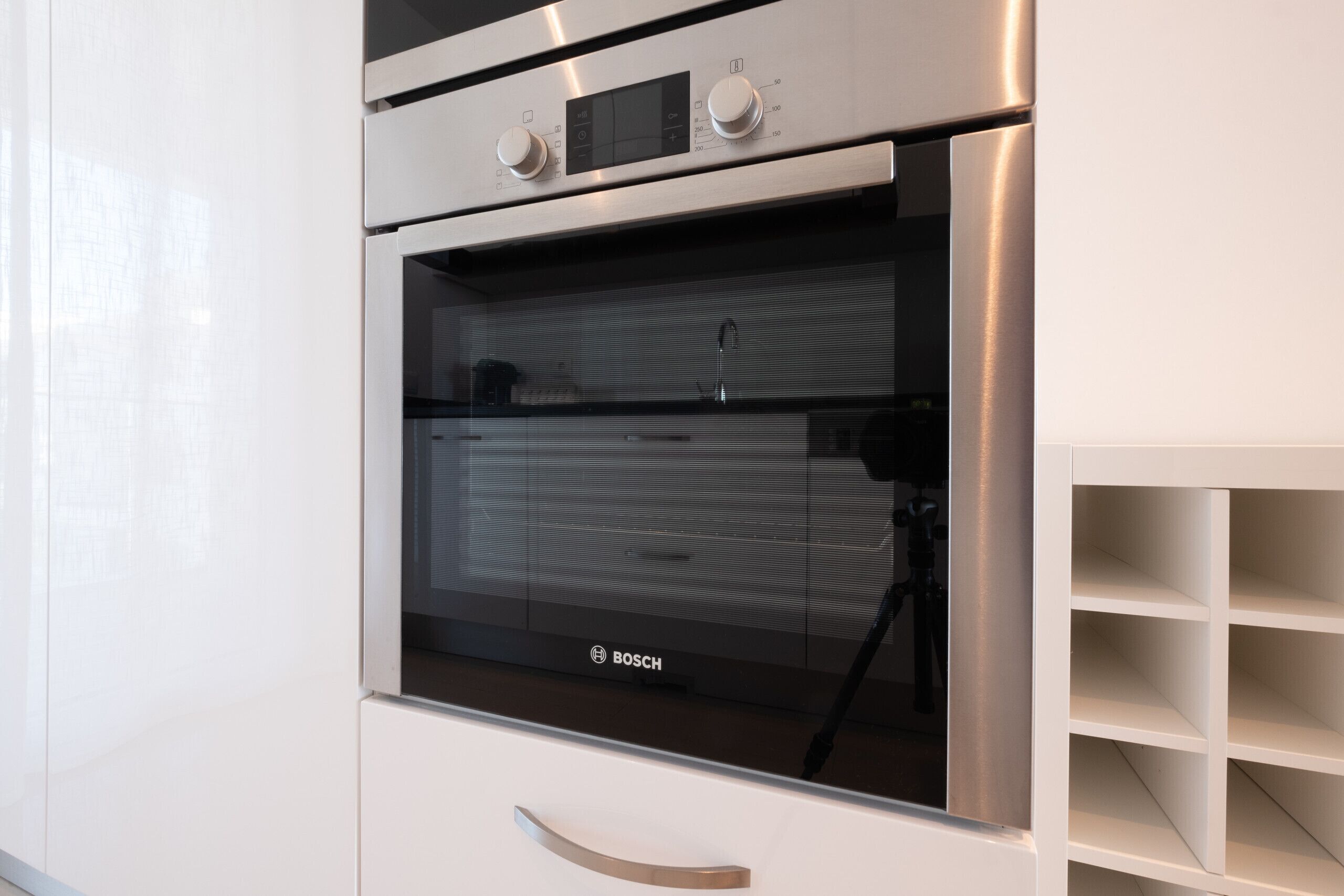 A modern kitchen with a Bosch oven, stainless steel appliances, and a minimalist design.