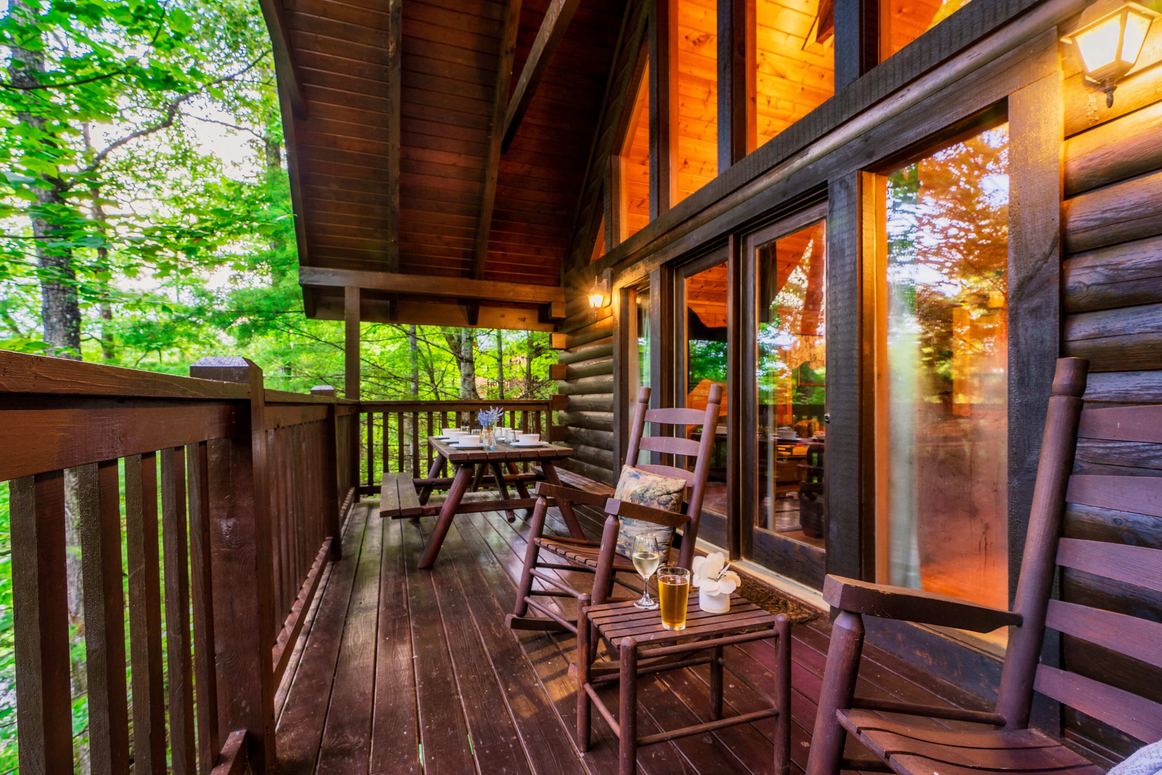 A wooden deck with a table and chairs, overlooking a forested area.