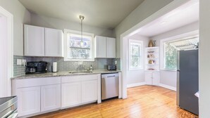Une cuisine moderne avec des meubles blancs, un lave-vaisselle et un réfrigérateur noir.