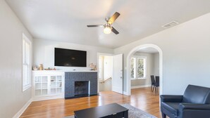 Un salon spacieux doté d’une cheminée, d’un téléviseur à écran plat et d’un ventilateur de plafond.