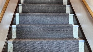 A carpeted staircase with wooden handrails, leading to a room with a patterned curtain. - 4 Bedroom Apartment above Wilzke's Pub - Neighborhood Bar. (Menasha)