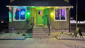 A two-story building with a neon sign reading "Wilzke's Pub" and a green door. - 4 Bedroom Apartment above Wilzke's Pub - Neighborhood Bar. (Menasha)