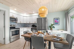 Enjoy meals at the dining table, surrounded by stainless steel appliances and white cabinetry.