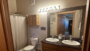 Une salle de bain avec deux lavabos, des toilettes, une douche et un miroir.