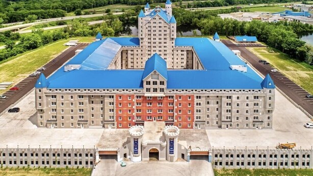A large, historic building with a central tower, multiple wings, and a blue roof. - The Grand Castle Apartments (Grandville)