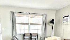 Een moderne woonkamer met een grijze modulaire bank, een beige fauteuil, een klein rond salontafeltje en een kamerkleed met een patroon.
