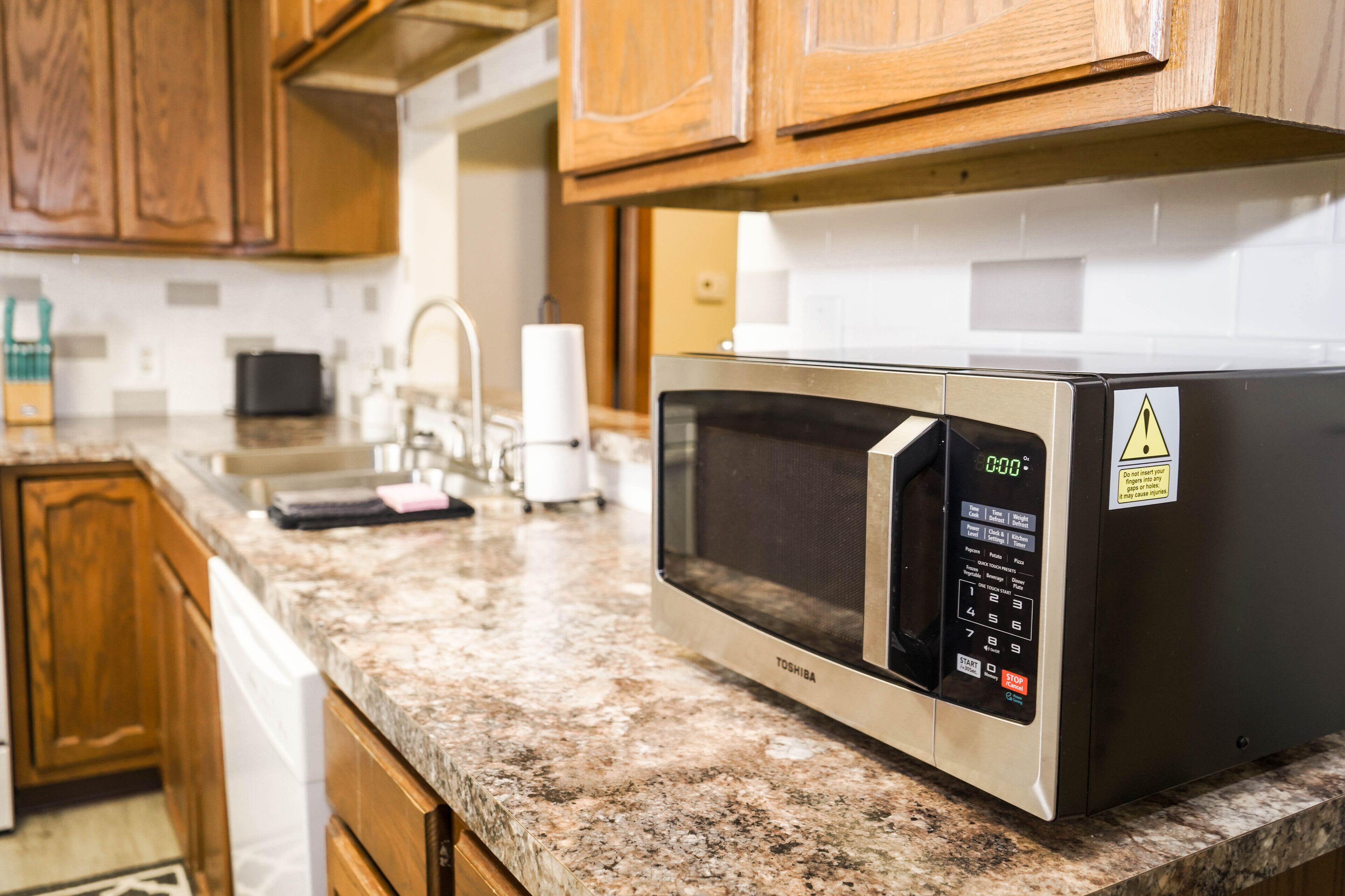 Une cuisine équipée d’un four à micro-ondes, de meubles en bois, d’un lave-vaisselle et d’un plan de travail muni d’un distributeur d’essuie-tout.