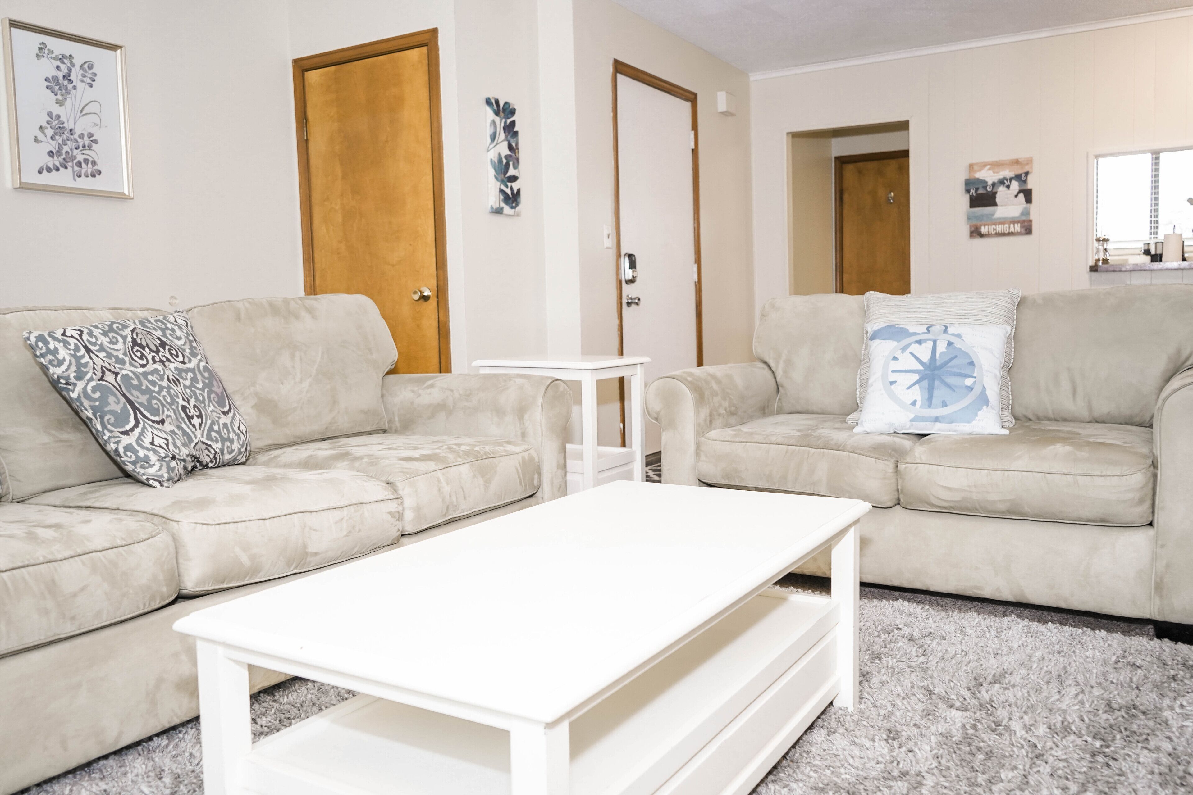 A living room with two beige sofas, a white coffee table, and a small white side table.