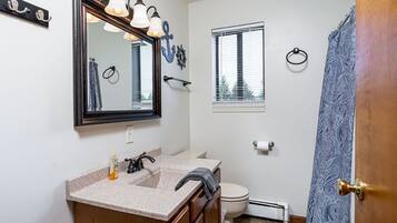 A bathroom with a vanity, sink, mirror, and toilet.