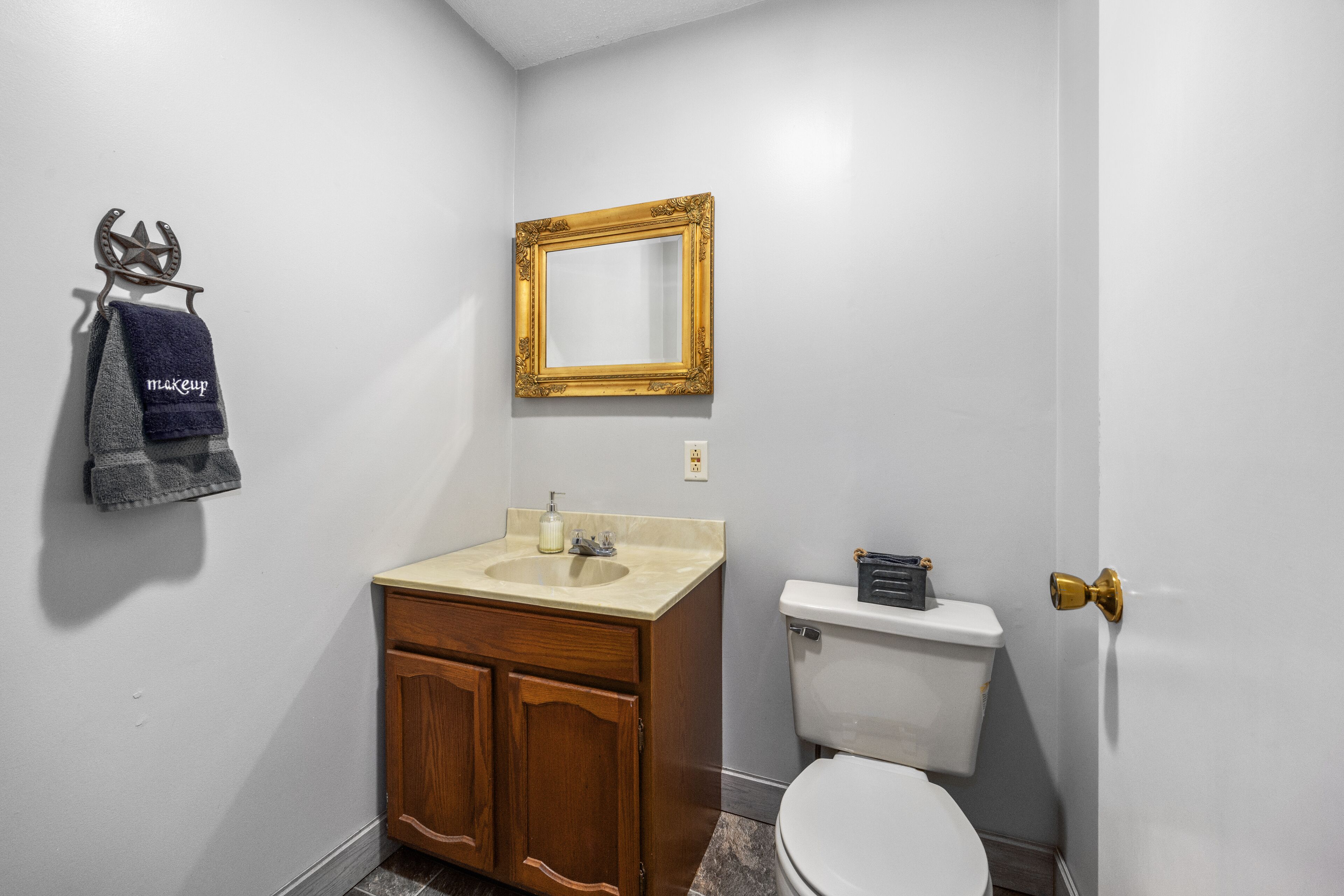 Une salle de bain équipée d’un lavabo, d’un meuble-lavabo, de toilettes et d’un miroir agrémenté d’un cadre décoratif.
