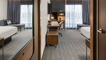 Habitación de hotel con dos camas, un escritorio, un televisor y un minibar.