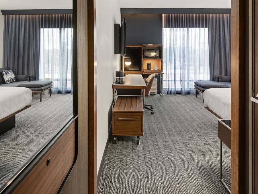 Habitación de hotel con dos camas, un escritorio, un televisor y un minibar.