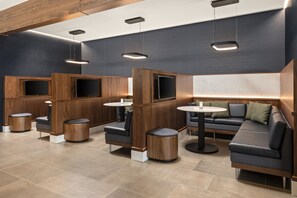 Un espace de détente moderne, doté de cloisons en bois, de sièges confortables et de téléviseurs intégrés.