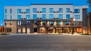 Un hotel Courtyard by Marriott con fachada moderna, múltiples ventanas y un área de entrada bien iluminada.