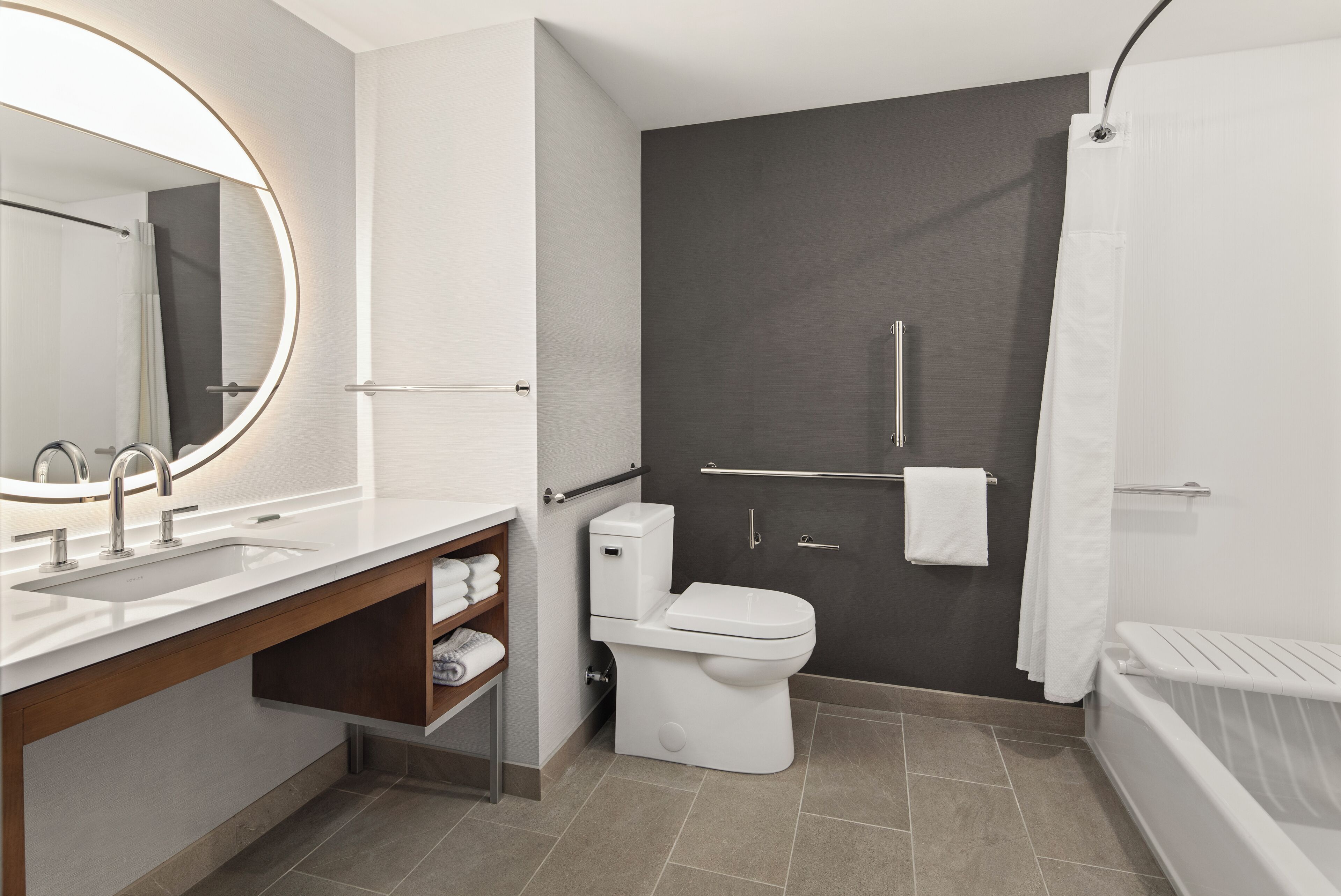 A modern bathroom with a white sink, mirror, and toilet.