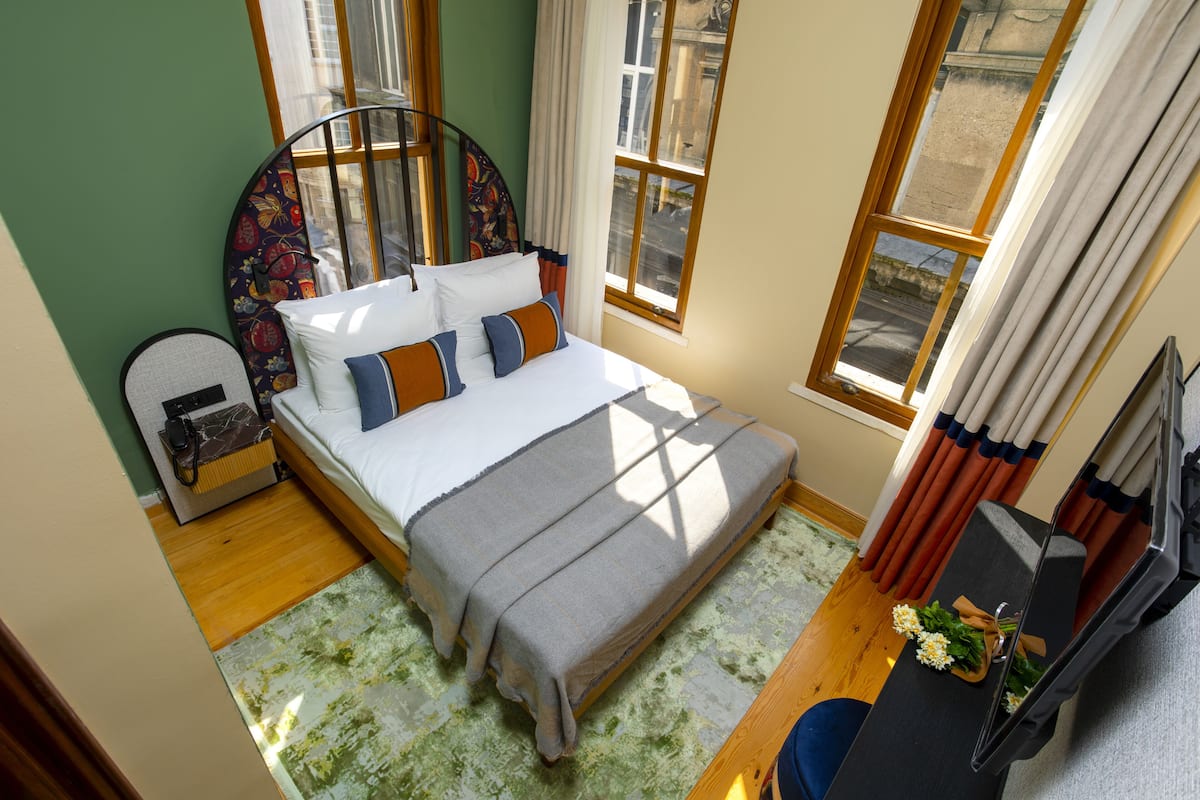 A bedroom with a bed, a desk, and a window.