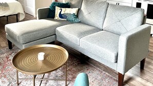 A modern living room with a grey sectional sofa, a round coffee table, and a patterned rug.