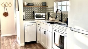 A compact kitchen with white appliances, a microwave, a stove, and a dishwasher.