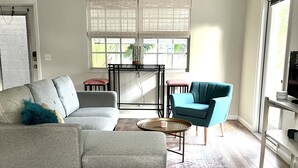 A modern living room with a grey sectional sofa, a teal armchair, a coffee table, and a patterned rug.