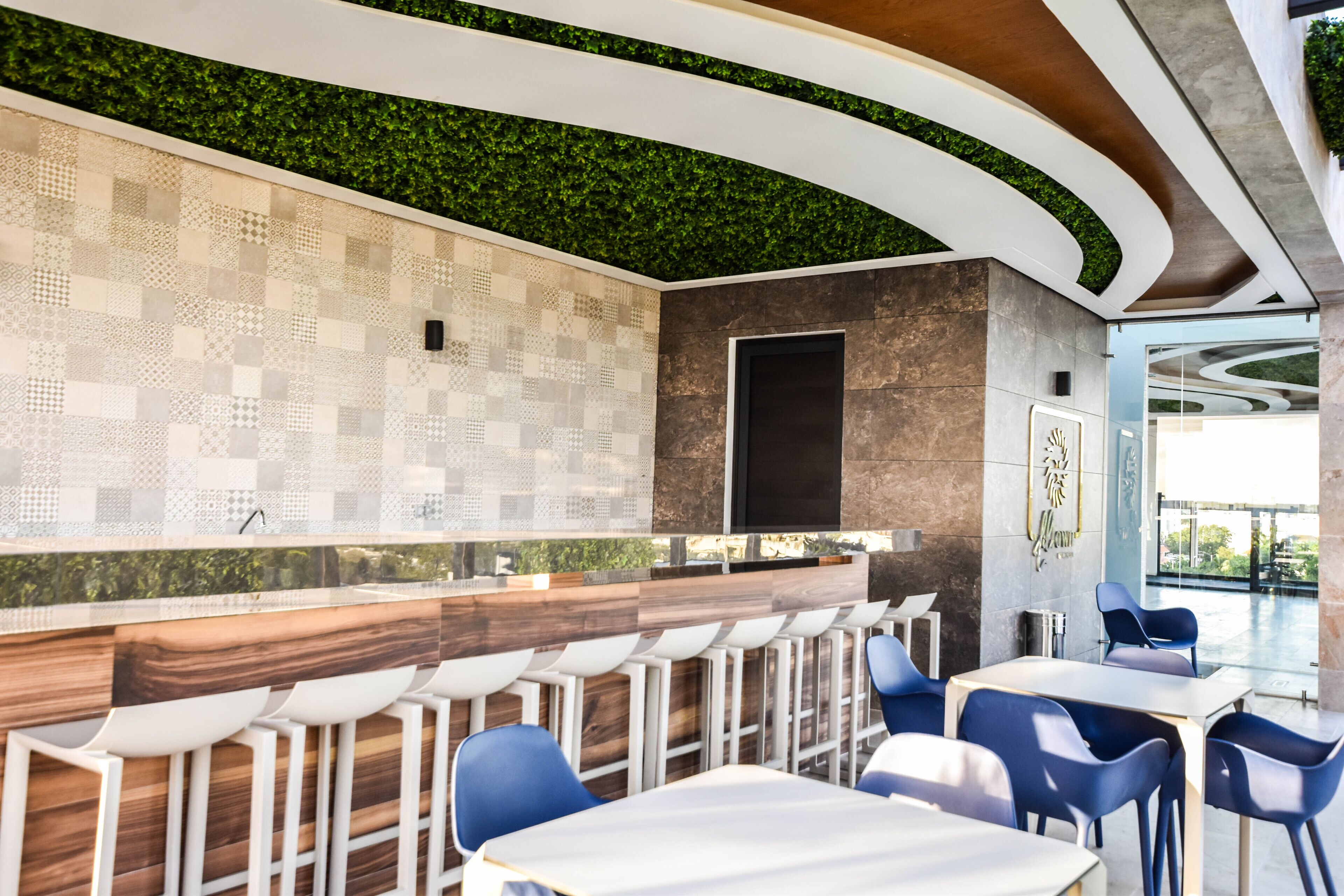 A modern restaurant with a patterned wall, green ceiling, and bar seating.