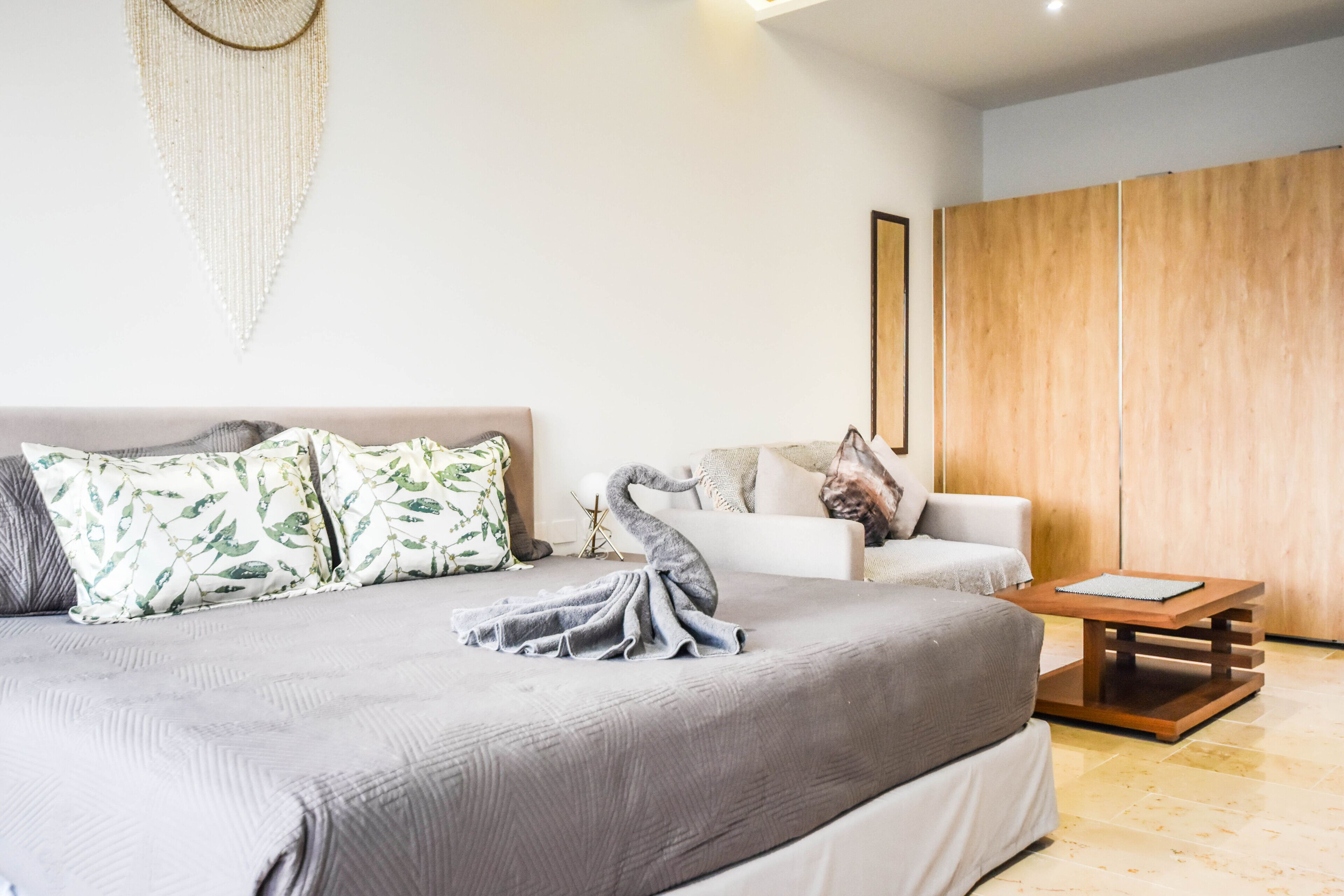 A modern bedroom with a large bed, a wooden wardrobe, and a small table.